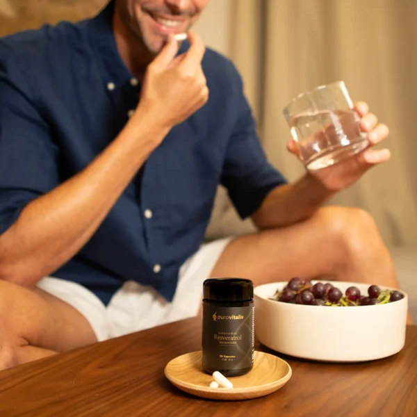 Supplément de resvératrol micronisé liposomal. Image montrant un homme prenant une capsule à côté de raisins et d'une bouteille de purovitalis.