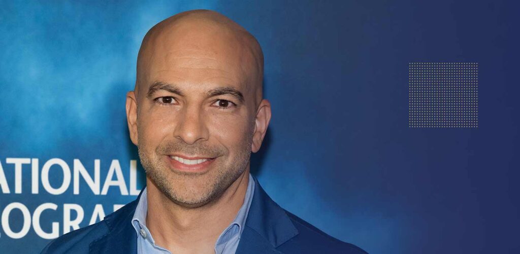 Portrait of Dr. Peter Attia with books and supplements in the background, emphasizing his contributions to nutrition and his authored book.