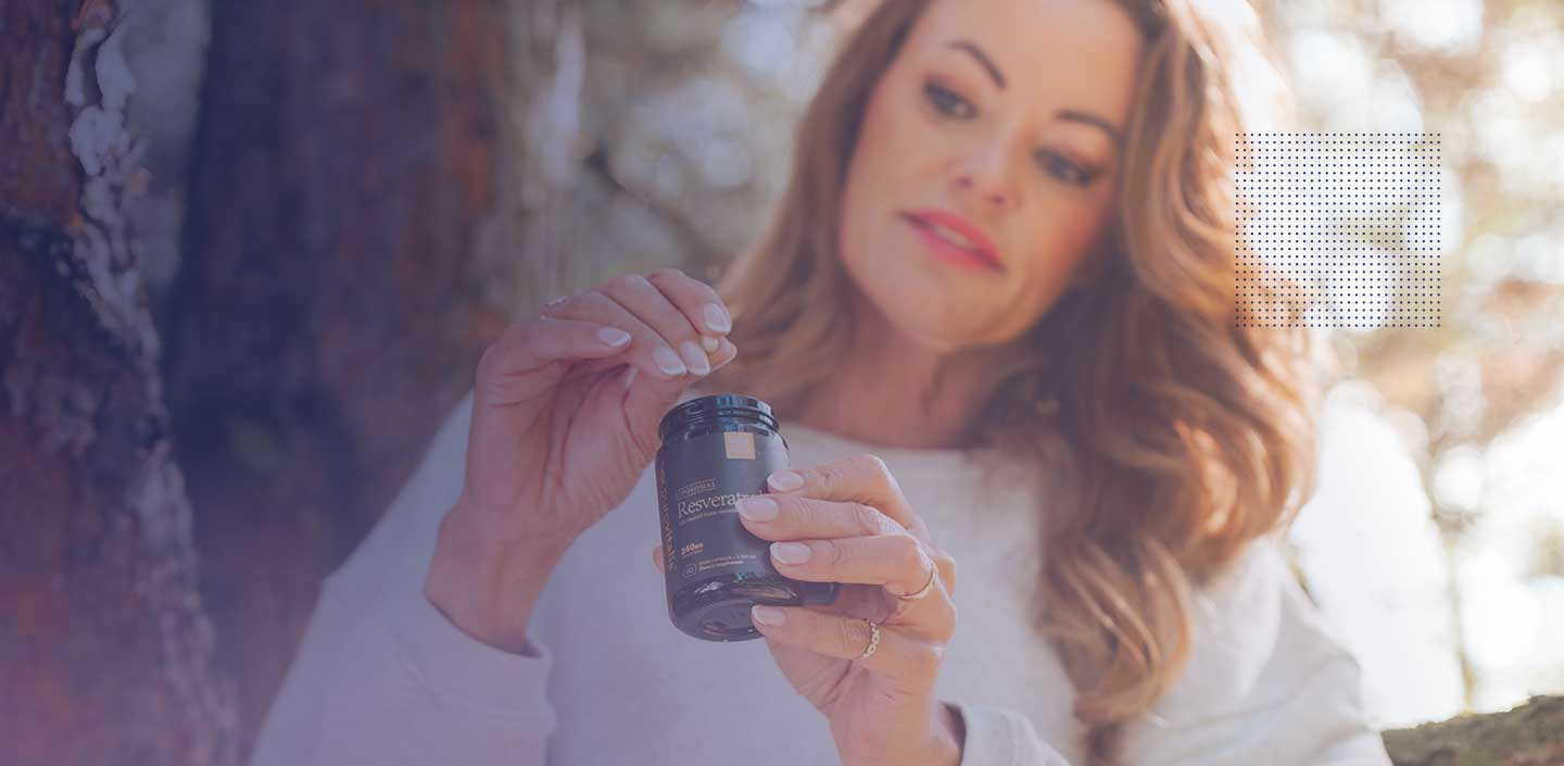 A woman holding a bottle of resveratrol capsules, showcasing its potential for skin care.