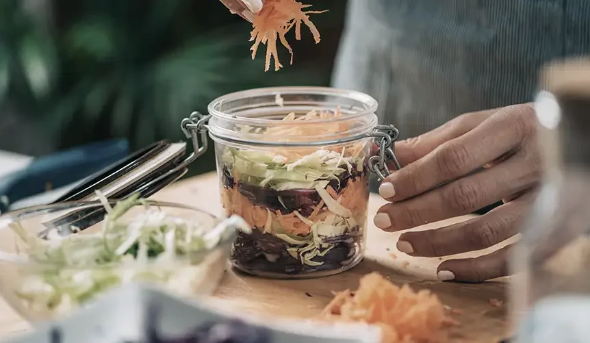 Et udvalg af probiotikarige fødevarer som yoghurt, kimchi, surkål og kombucha står på et rustikt bord. Disse fødevarer fremmer tarmhelsen, og forskning viser, at det kan have en positiv indvirkning på aldringsprocessen og bidrage til longevity ved at holde tarmmikrobiomet i balance. Lær, hvordan en sund tarm kan bidrage til dit generelle velvære og understøtte et længere og sundere liv.