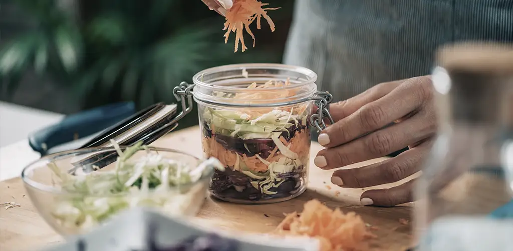 An assortment of probiotic-rich foods, including yogurt, kimchi, sauerkraut, and kombucha, displayed on a rustic table. These foods support gut health, which research shows can positively influence aging and promote longevity by maintaining a balanced gut microbiome. Learn how a healthy gut can contribute to overall well-being and support a longer, healthier life.