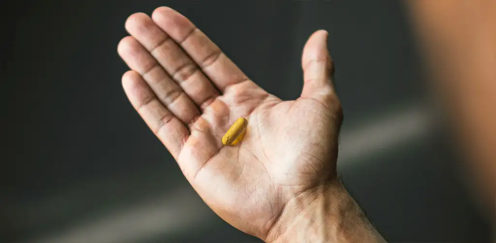 Dihydroberberine capsule on hand. Article header image where we explain the differences between berberine and Dihydrobererine