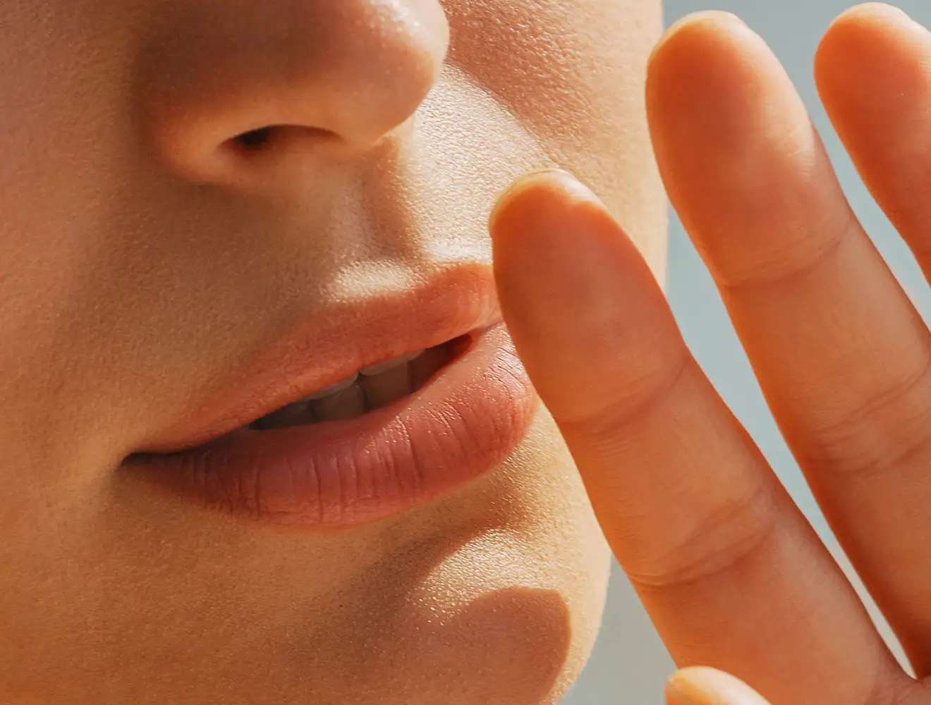 Close-up shot of a person's lips and nose with fingers held close to the mouth.