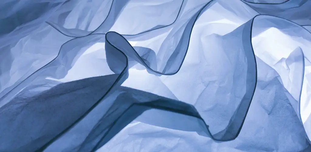 Light linen fabric floats in the air with the sun reflecting on it