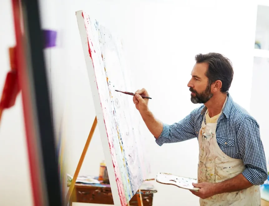 Un bărbat de vârstă mijlocie care se dedică picturii creative, contribuind astfel la sănătatea creierului, la concentrarea mentală și la funcțiile cognitive.