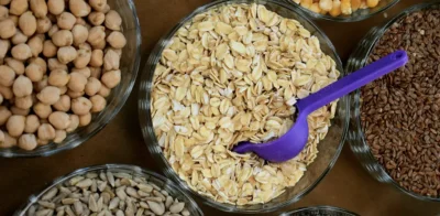 Apropiere de ovăz, năut și semințe în boluri mici cu o lingură de plastic violet în ovăz