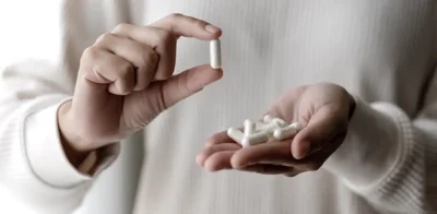 Eine Person, die weiße GlyNAC-Kapseln in der Hand hält, illustriert die antioxidativen Ergänzungsmittel, die die Zellgesundheit und longevity unterstützen.