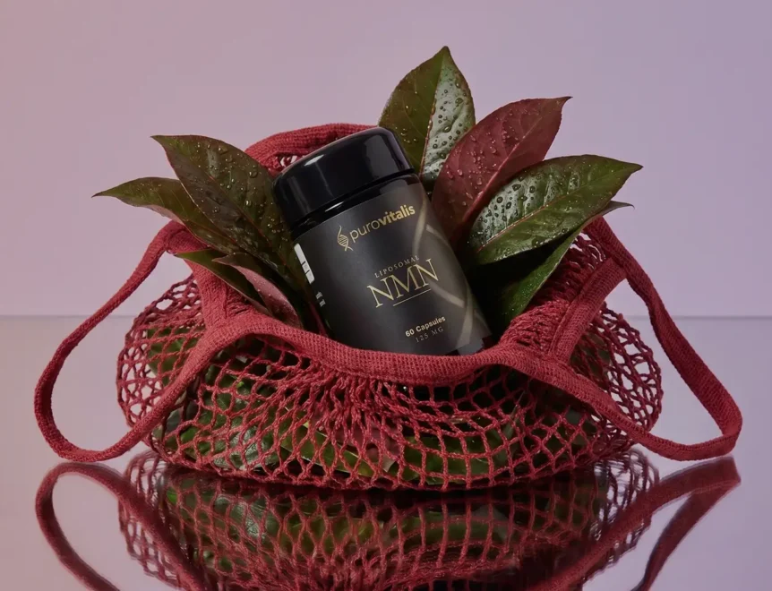 Een zwarte fles Purovitalis Liposomal NMN, omringd door verse, met dauw bedekte groene en roodachtige bladeren in een rode geweven boodschappentas.