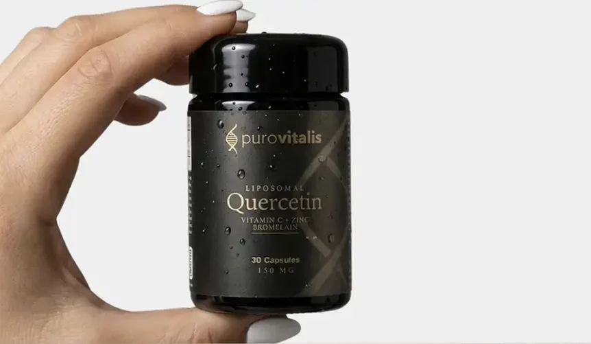Une main tient un flacon noir de la marque Purovitalis portant la mention “ Liposomal Quercetin avec vitamine C, zinc et bromélaïne ”, indiquant qu'il contient 30 gélules, sur un fond clair.