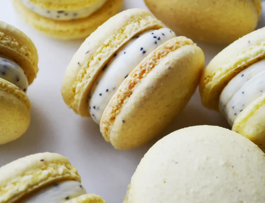 Close-up of yellow macarons with white cream filling and poppy seeds representing ultra-processed food.