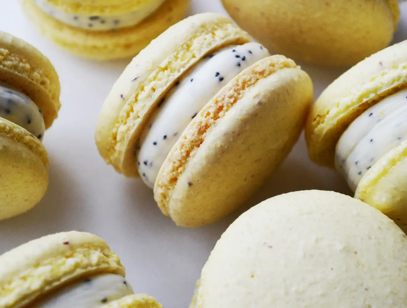 Close-up van gele macarons met een vulling van witte room en maanzaad, die ultra-bewerkte voedingsmiddelen voorstellen.
