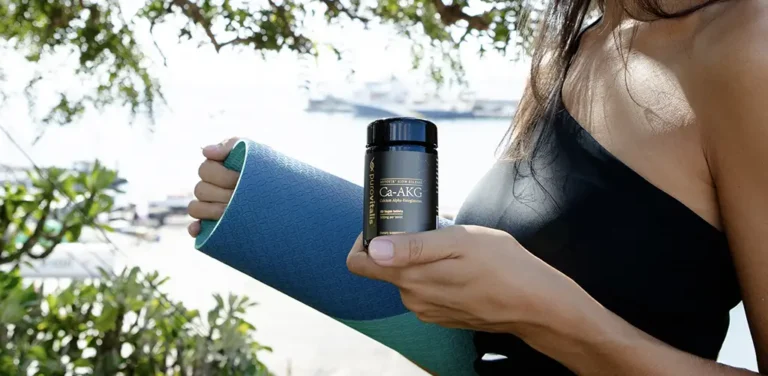 Vrouw die buiten met een yogamat een flesje calcium-alfa-ketoglutaraat (Ca-AKG) in haar hand houdt