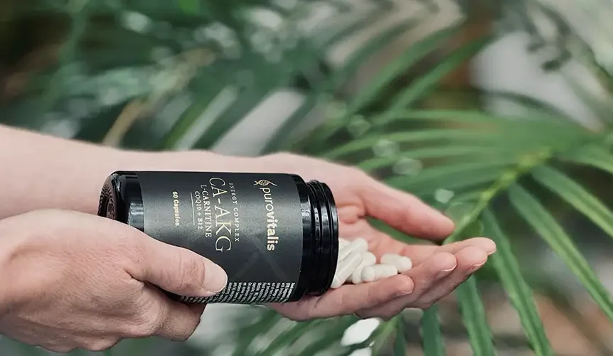 Person pouring Purovitalis Ca-AKG capsules with L-Carnitine and Vitamin B12 into their hand, highlighting longevity and cellular energy support.