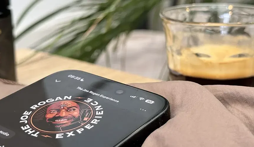 Listening to The Joe Rogan Experience podcast on a smartphone, related to Joe Rogan supplements and longevity discussion