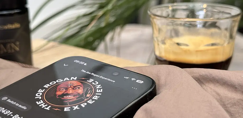 Luisteren naar de podcast ‘The Joe Rogan Experience’ op een smartphone, in verband met longevity Joe Rogans supplementen en longevity