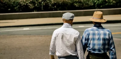 two elderly people walking outdoors on a sunny day.