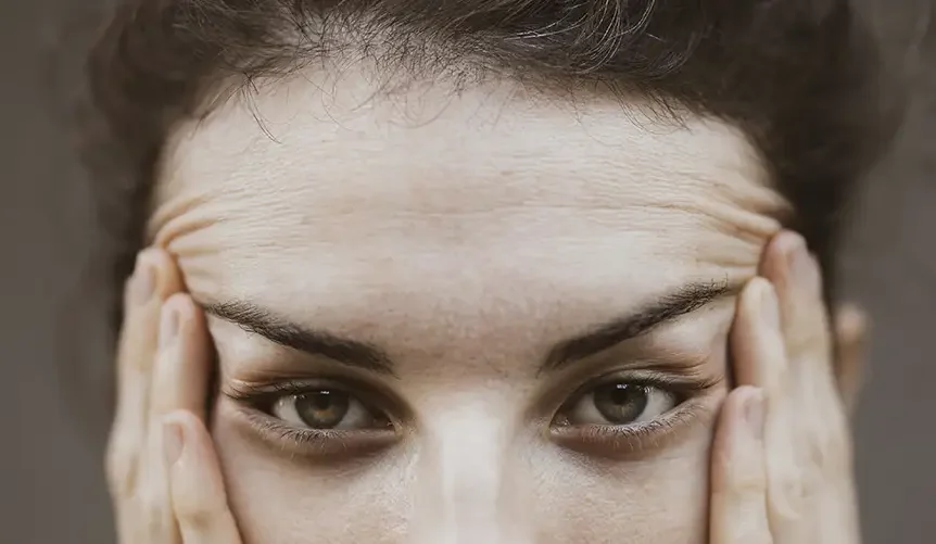 Close-up of a middle-aged woman touching her forehead showing fine lines and skin changes during menopause